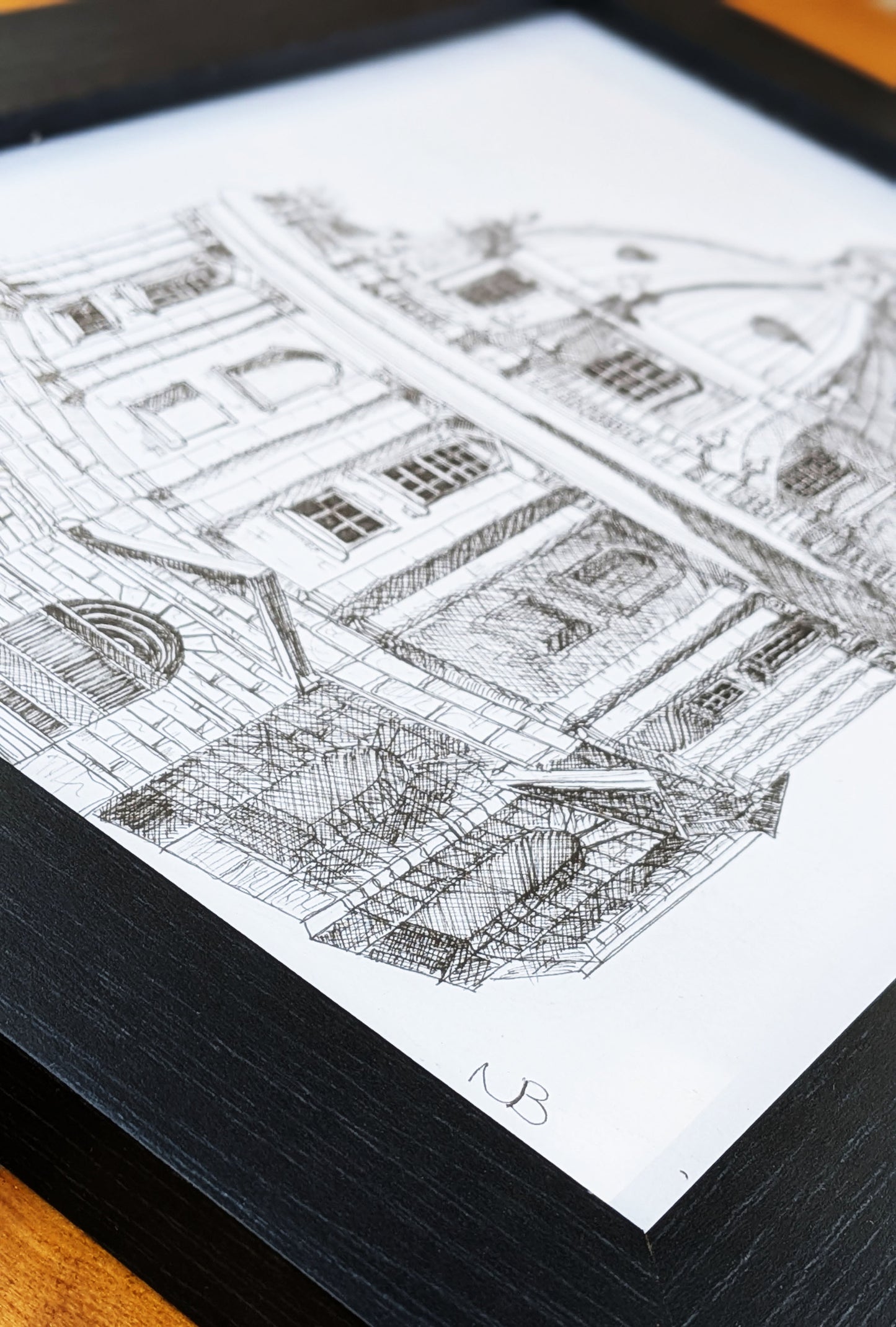 Framed black and white architectural drawing on a wooden surface