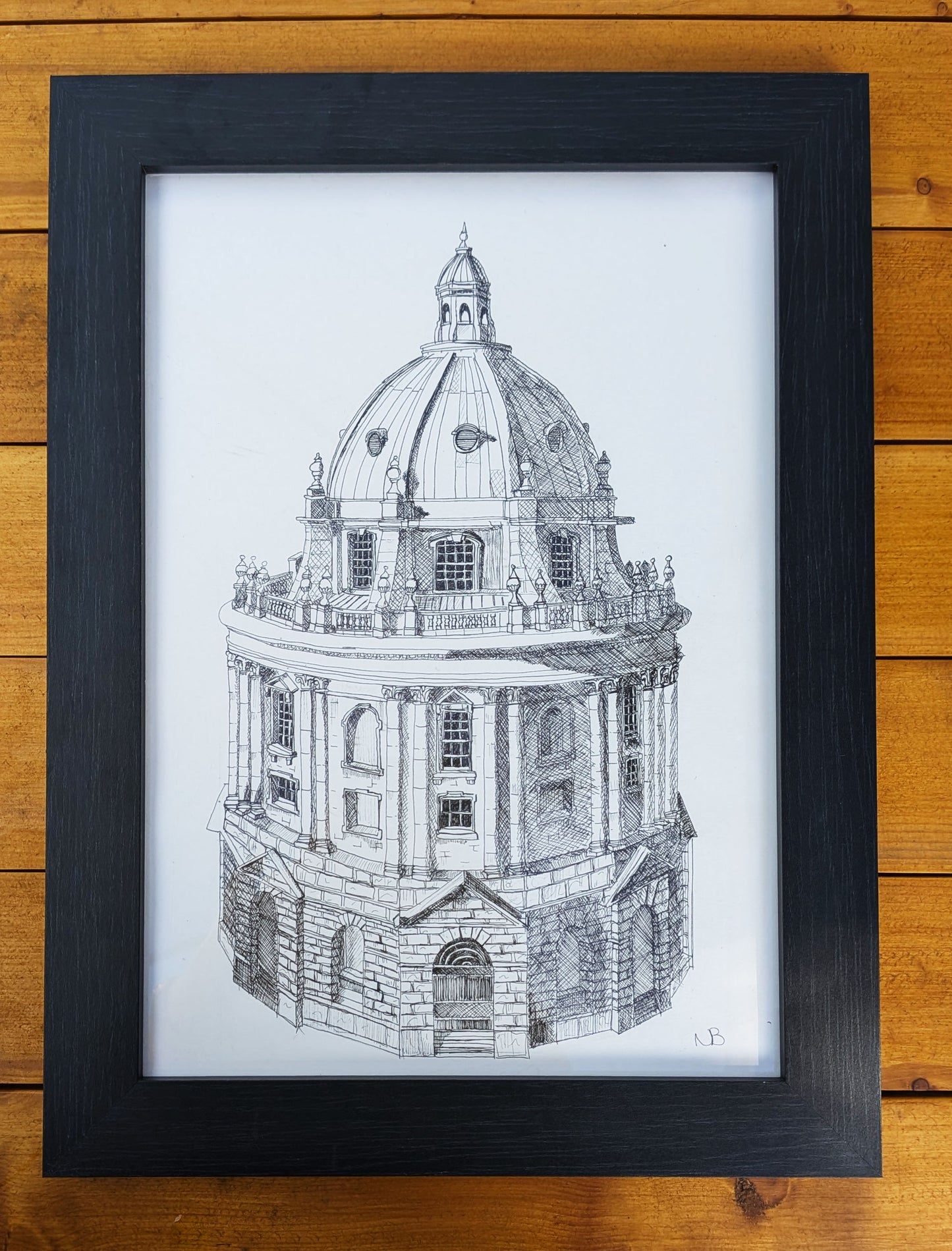 Framed black and white architectural drawing of a dome on a wooden surface