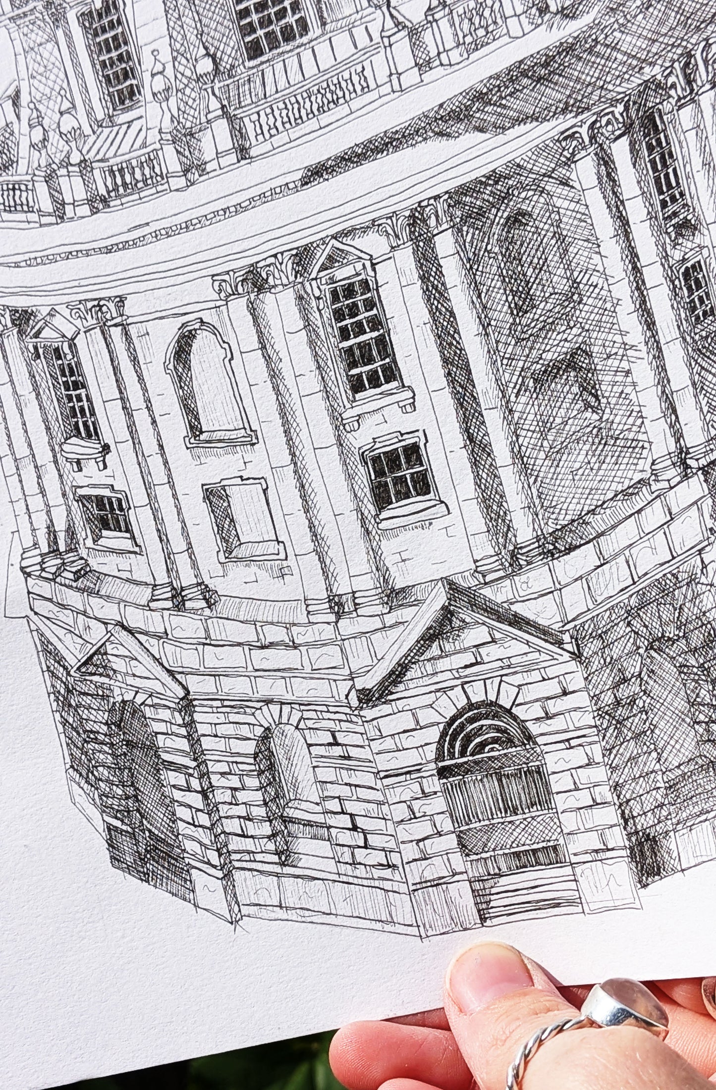 Close-up of a detailed black and white architectural drawing held by a hand.