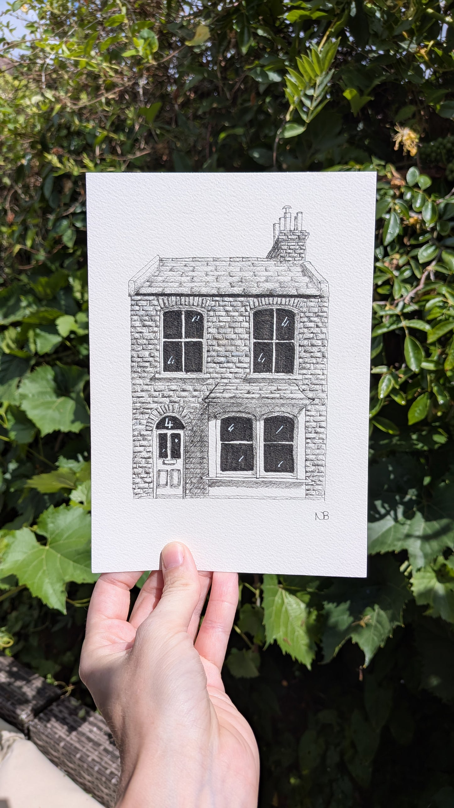 hand holding an a5 fineliner drawing of a terraced brick house