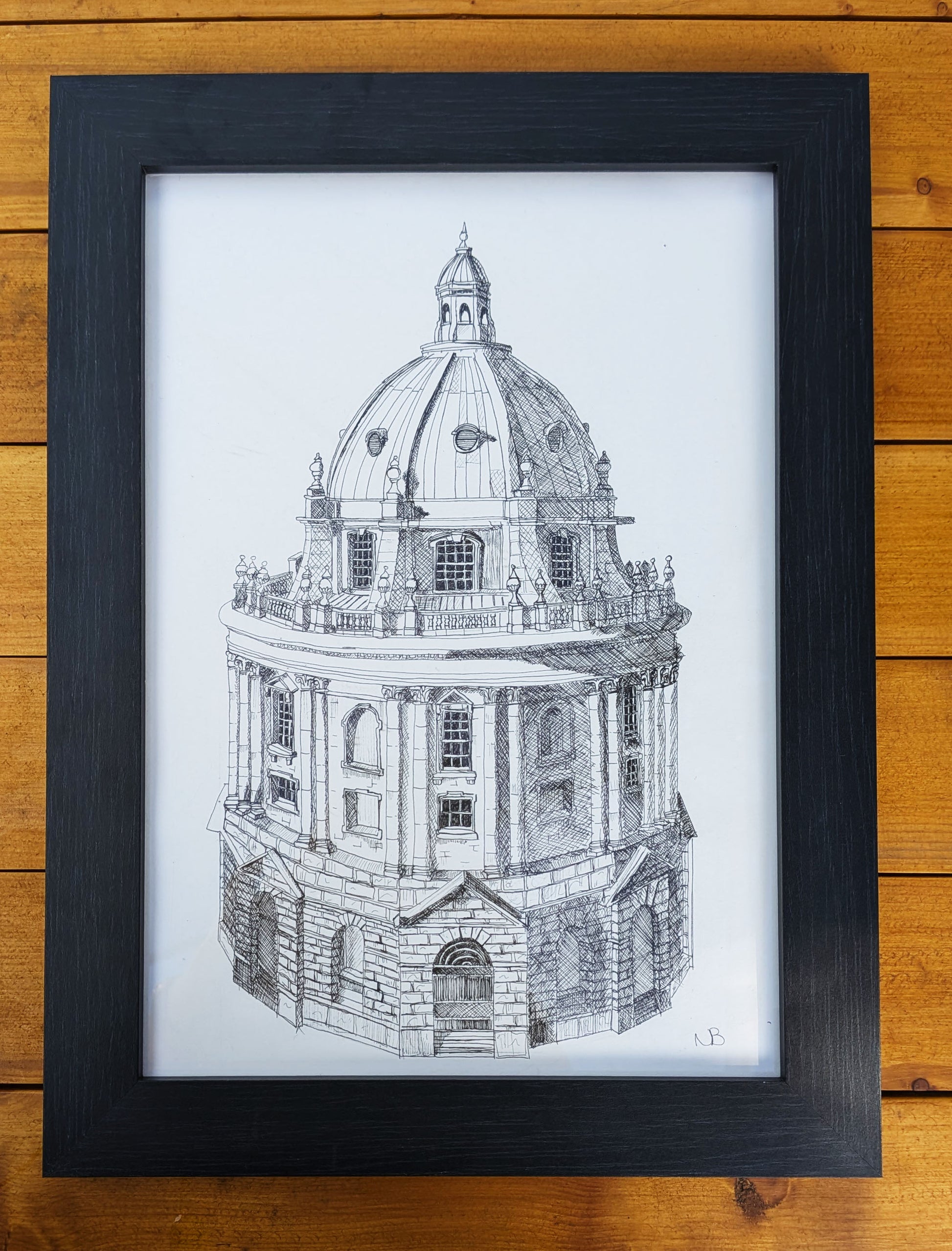 Framed black and white architectural drawing of a dome on a wooden surface