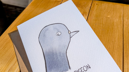 Card with a penguin illustration on a wooden table.