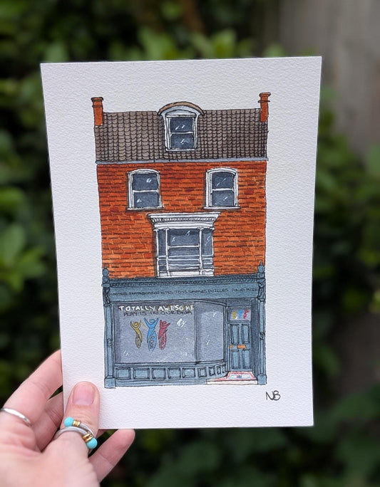 hand holding a painting of a toy shop named 'totally awesome toys'