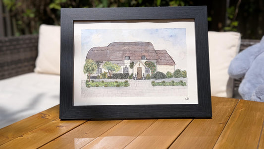 framed painting of a thatched roof wedding venue cottage