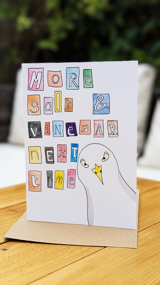 Card with a cartoon seagull and colourful text on a wooden surface