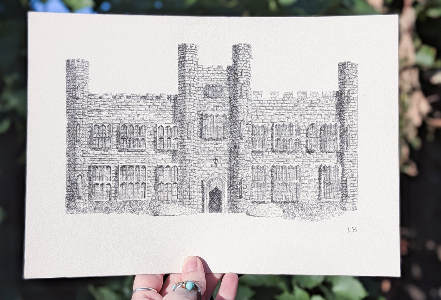 Hand-drawn illustration of a castle held against a natural background